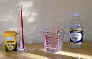 Activity set up showing a box of chalk, a graduated cylinder, a measuring glass and a bottle of vinegar