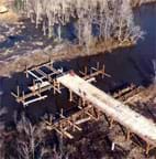 Photo of a wooden bridge in construction over a stream.