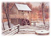Building with large wooden wheel partially in a snowy river.