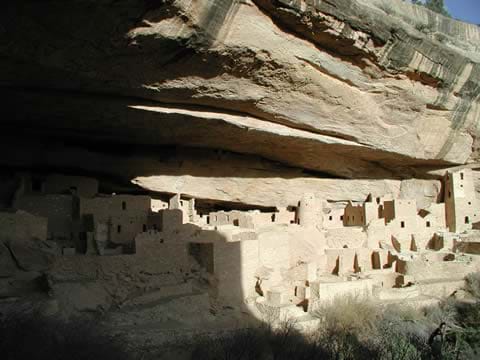Photo of stone structures under a protective rock cliff.