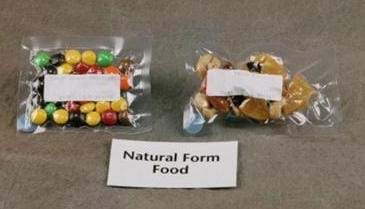 Vacuum-sealed bags of M&Ms and dried fruit and nuts. A sign below the two bags reads: "Natural Form Food."