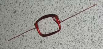 Photo shows red, magnet wire coiled into the shape of a rectangle. 