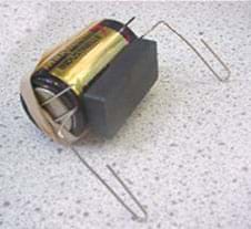 Photo shows the ceramic magnet on the side of the battery, along with the paper clips and rubber band. 