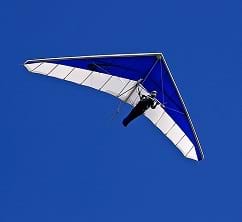 A photograph shows a man flying a glider through the sky.