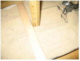 Photo shows a ruler placed vertically into the bottom of the furrow next to another ruler placed across the pan of sand, resting on the pan edges, providing a consistent level to which the depth can be measured.
