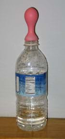 Photo shows a clear plastic water bottle containing a few cm of clear liquid and a pink balloon attached to the neck to catch any rising gas.