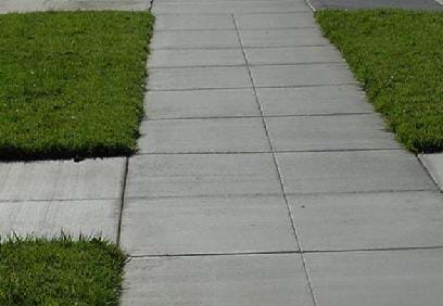 Photograph of a sidewalk with many vertical and horizontal grooves cut into the concrete.