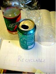 Photo shows a plastic drink bottle, aluminum soda can, plastic wrap and a plastic container, all depicting recyclable trash.