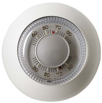 Photo shows a round, wall-mounted thermostat with a temperature dial.