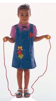 A photograph of a young girl standing still and holding a jump rope.