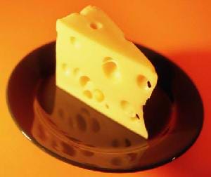A photograph of a wedge of Swiss cheese on a brown plate.