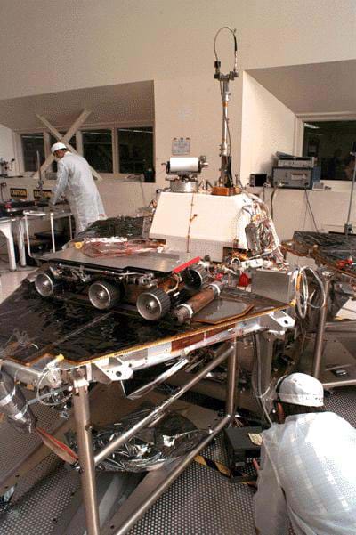 A photo of  NASA engineers assembling the Mars Pathfinder lander and the Sojourner rover in a lab at NASA's Jet Propulsion Lab (JPL).