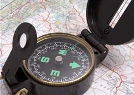A photograph shows a compass on a paper map.
