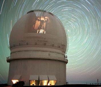 A photograph of an observatory at night with the star trails in the night sky; they look like rings of concentric circles.