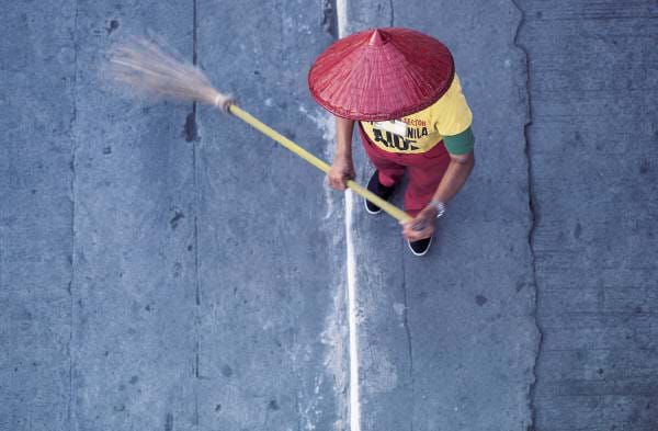 Photograph from above, showing a person sweeping with a broom.