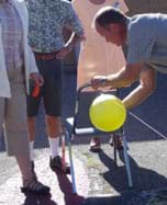 Photo shows a person positioning an inflated balloon to be released along a taught string attached to the back of a chair.
