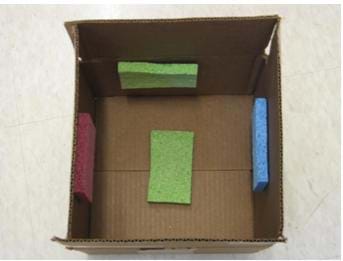 Photo looking into a box from above with sponges attached to the bottom and inside four walls.