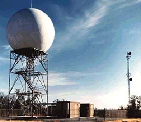 Photo shows Doppler radar equipment, which looks like a giant white ball resting atop a three-story metal stair structure.