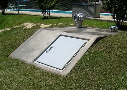 The image shows a concrete slab with a door and vents, in the ground. This is an opening to an underground structure, which can provide a safe location during a tornado.