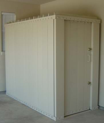 The image shows a small room, resembling a shed, inside a building. It is equipped with steel walls, a concrete foundation, and a removable door.