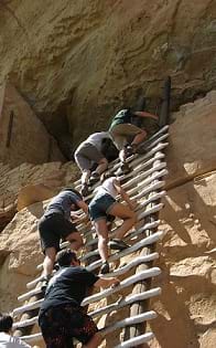 People climbing a ladder at the Mesa Verde National Park.