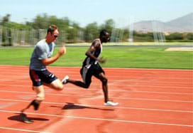 Two men run side-by-side on a track, one with a prosthetic leg.