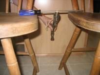 Photo shows a hammer suspended upside down by string from a long screwdriver bridged between two chair seats.