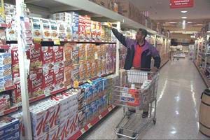 A photograph shows a man pushing a cart in the breakfast cereal aisle of a grocery store