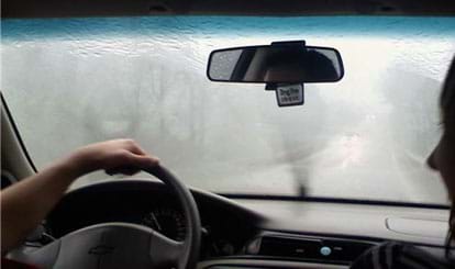 Photo shows rain on windshield, obscuring the view of the road ahead.