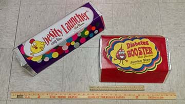 Two large candy bars lay on the floor next to a Home Depot yardstick and a ruler.