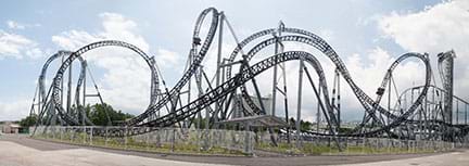 A wide photograph shows the Takabisha roller coaster in the Fuji-Q Highland theme park, Fujiyoshida, Yamanashi, Japan, which is famous for being the steepest coaster in the world with its 121° drop angle and for its $26 million cost. The photo shows a complicated, multiple curving and looping roller coaster rail structure.