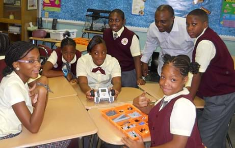 A photograph shows six students and a teacher working with a LEGO robot.