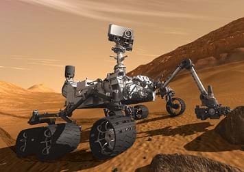 An artists' illustration of a robot on wheels with a camera and sensors on a red-dirt surface of Mars.