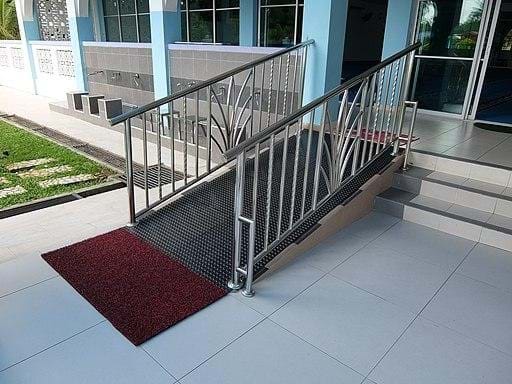Image of a small wheelchair ramp on an incline leading up to the front doors of a building.