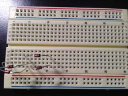 A photograph shows the wires of four diodes inserted into various holes in a plastic breadboard.