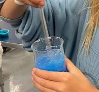 Picture of a blue gel being stirred by a glass rod in a graduated cylinder.