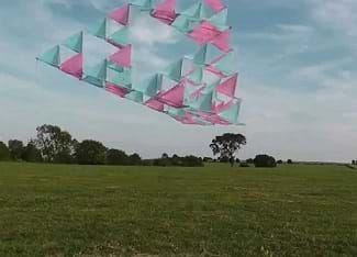A tetrahedral kite flying in the air.  