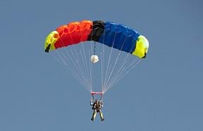 A skydiver releasing his colorful parachute in the sky.