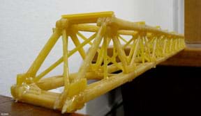 A photograph shows a student-created truss-type bridge structure made with dry spaghetti noodles glued together. 
