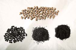 Photo shows four piles: Poultry manure pellets are light brown and short cylinders in shape. Three piles of dark materials are activated carbon in pellet, granular and powdered forms (increasingly fine).