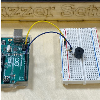 Photo of a buzzer hardwired into a breadboard in series with a resistor and an Arduino. 