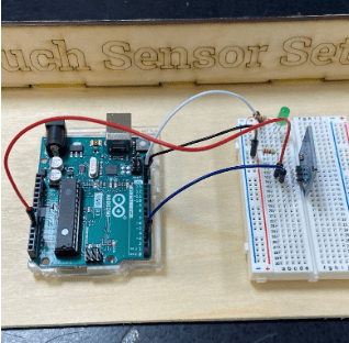 Photo of a sensor hardwired into a breadboard with an LED, two resistors, and an Arduino.
