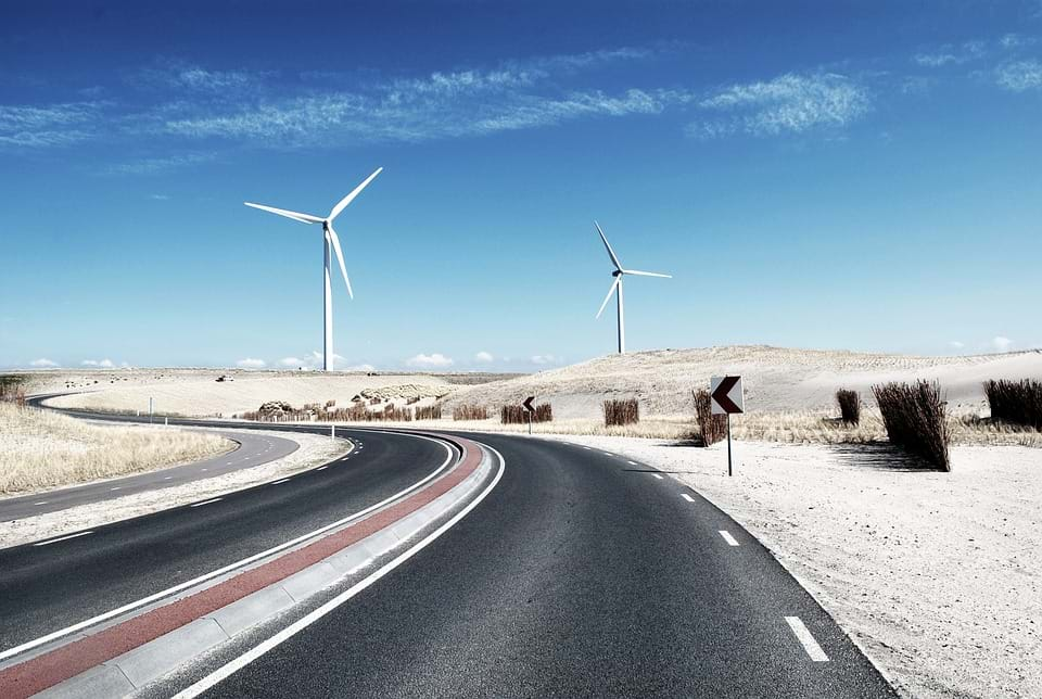 A photo of a winding road with two white windmills.