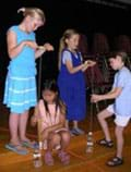 Photo shows two pairs of students holding human power apparatuses. The teams are ready to each lift a mass of water to determine their own power. 