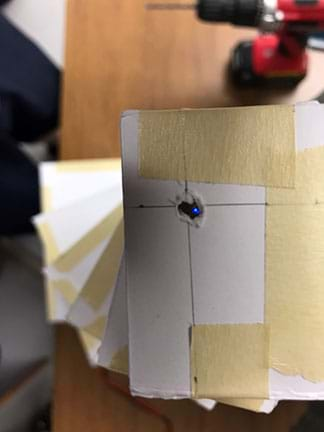 An image of stacked cardstock boxes. Light can be seen from the bottom floor through correctly placed holes drilled for the elevator shaft.