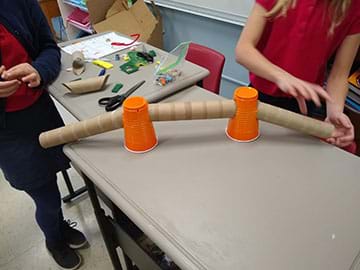 Students showing their tunnel made from to cups as support towers and paper towel tubes and the cross walk.