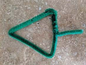 A green pipe cleaner is shown shaped in the form of an arrow.