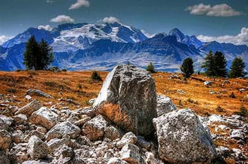 Two images: A photo shows large boulders in a foreground valley with a mountain backdrop.