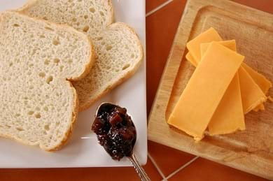 A close up of sliced cheddar cheese on a cutting board.