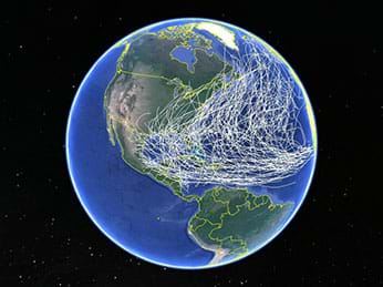 A photograph shows the Earth from space, specifically North and South America with numerous white lines showing the paths of past hurricanes through the Atlantic Ocean to the Gulf of Mexico and the U.S. East Coast.